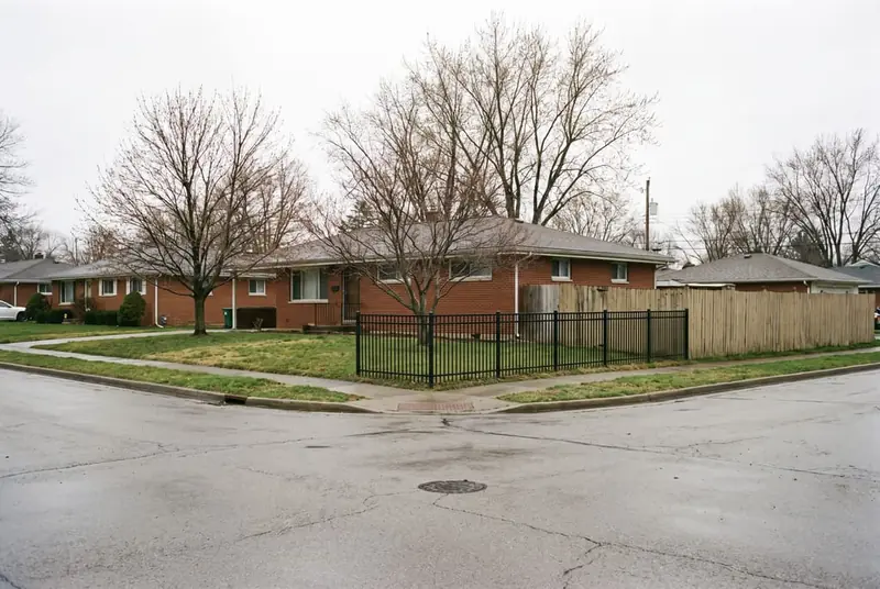 Corner lot where a low open aluminum fence along the side street steps up to a taller privacy fence behind the house