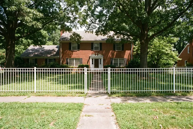 4 ft white aluminum front fence with a walk gate facing the street in front of a 1960s center-hall colonial