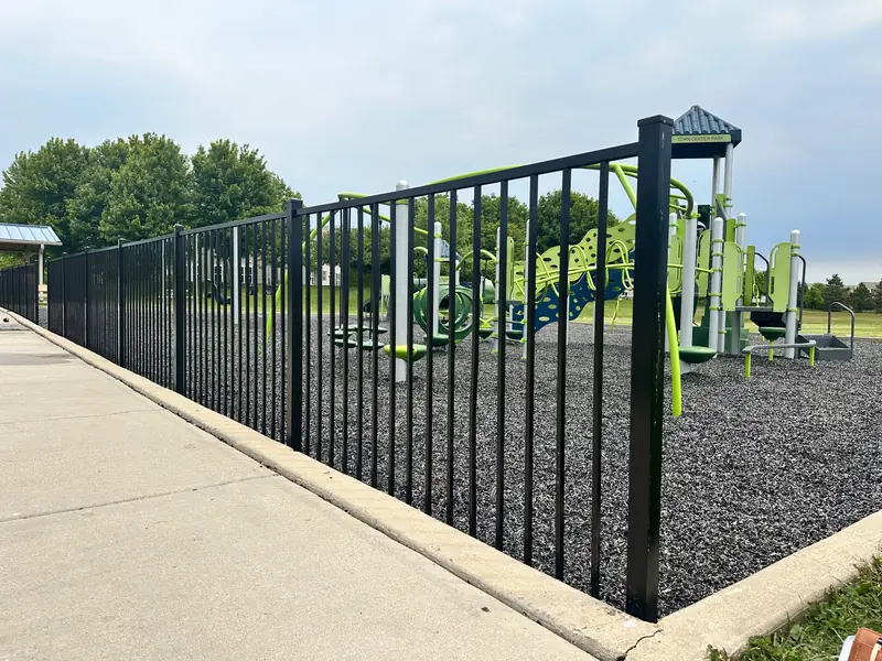 Black aluminum fence enclosing a community playground