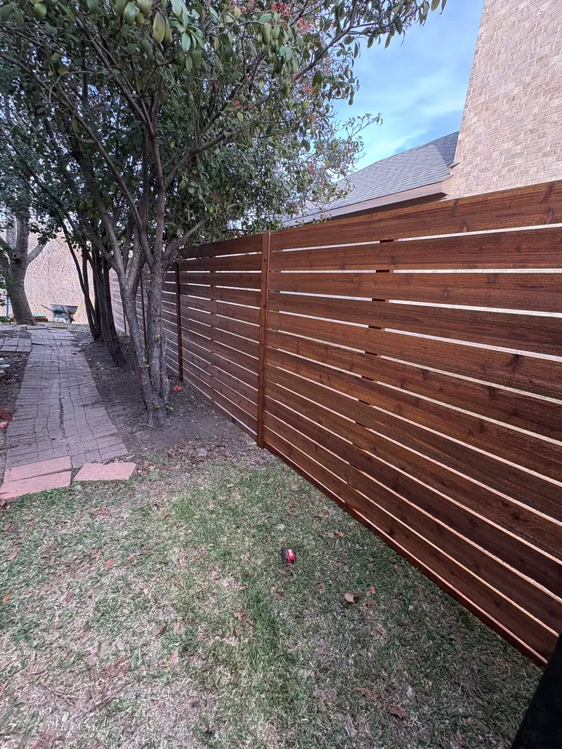 Horizontal stained wood fence with narrow gaps along a side yard